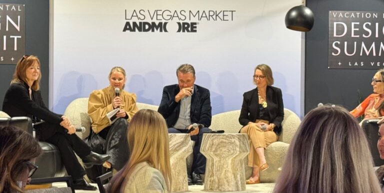 Panel discussion on stage at the Vacation Rental Design Summit during Las Vegas Market, with four speakers seated on cream boucle chairs answering audience questions